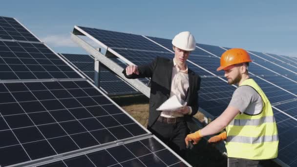 Бизнесмен и рабочий вместе проверяют солнечные батареи снаружи — стоковое видео
