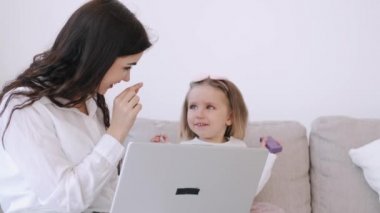 Anne ve küçük kızı bir dizüstü bilgisayarla çalışıyorlar.