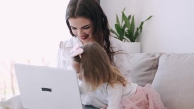 Anne ve küçük kızı bir dizüstü bilgisayarla çalışıyorlar.
