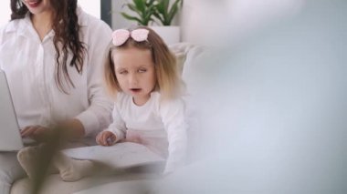 Küçük kız ve anne birlikte kanepede oturuyorlar.