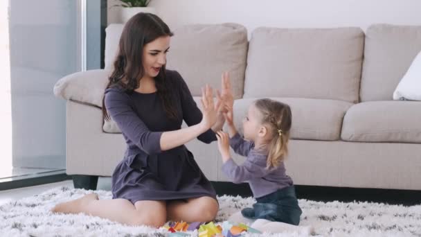 Mooie jonge moeder en dochter spelen in een moderne woonkamer — Stockvideo