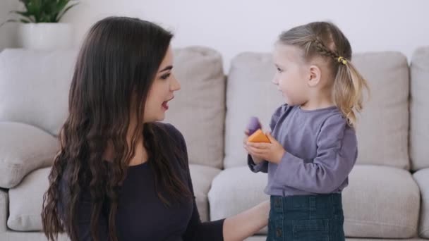 Csinos fiatal anya és lánya játszanak egy modern nappaliban — Stock videók