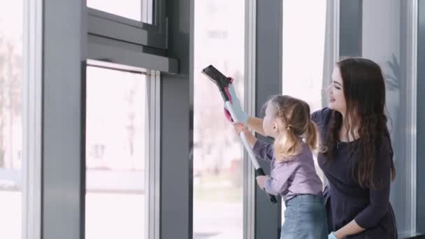 Το κοριτσάκι καθαρίζει τα παράθυρα με μια σφουγγαρίστρα με τη μητέρα της. — Αρχείο Βίντεο