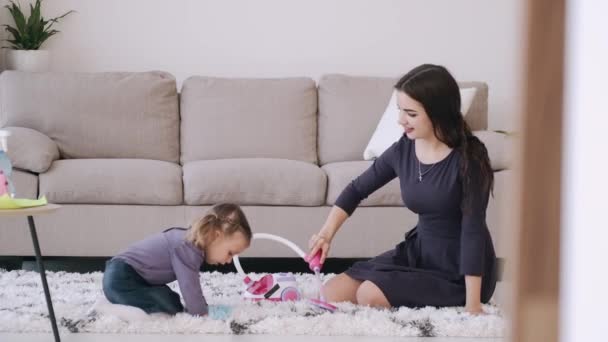 Мать и ребенок играют с игрушкой пылесоса в гостиной — стоковое видео