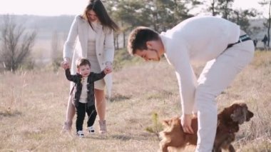 Oğlu ve köpeği olan mutlu bir aile tarlada yürüyor.