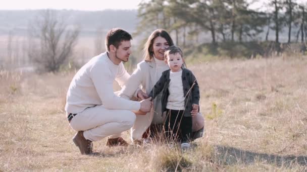 La familia feliz con un hijo pequeño está caminando en el campo durante la cuarentena. — Vídeos de Stock