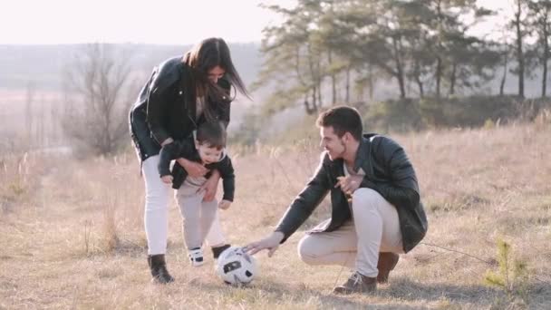 Glada föräldrar och en söt son spelar fotboll utanför — Stockvideo