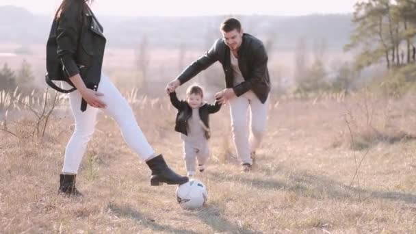 Padres felices y un lindo hijo están jugando al fútbol afuera — Vídeos de Stock