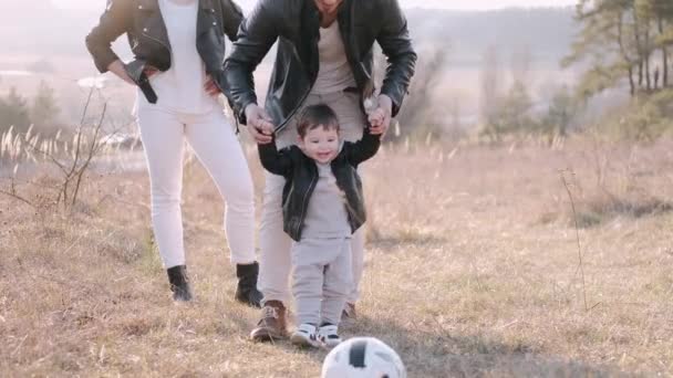 Pais felizes e um filho bonito estão jogando futebol fora — Vídeo de Stock