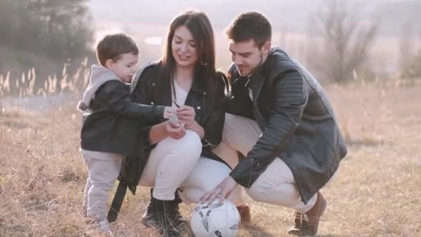 Ευτυχισμένοι γονείς και ένας χαριτωμένος γιος παίζουν ποδόσφαιρο έξω. — Αρχείο Βίντεο