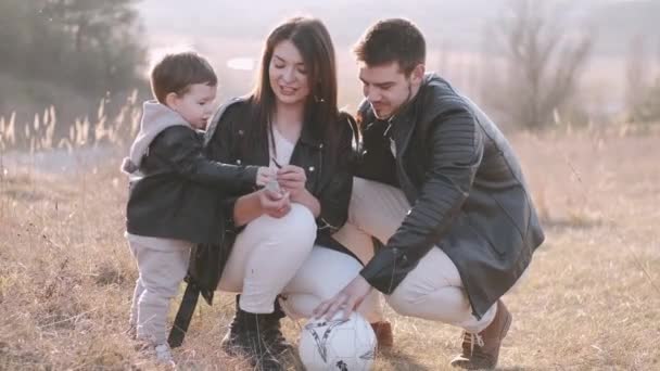 Pais felizes e um filho bonito estão jogando futebol fora — Vídeo de Stock