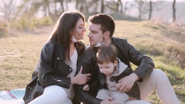 Familia joven con máscaras y un hijo en un picnic — Vídeos de Stock