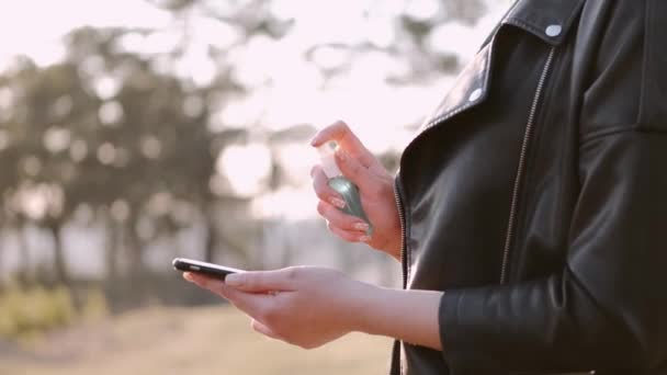 La mujer está rociando antiséptico en una pantalla del teléfono — Vídeo de stock