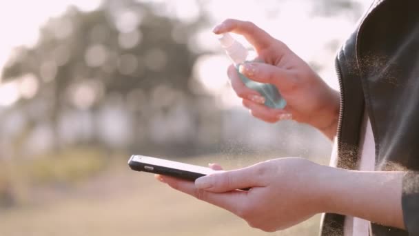 Ta žena rozstřikuje antiseptikum na obrazovku telefonu. — Stock video