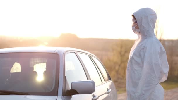 Eine Frau in Vollschutzausrüstung hält ein Auto an der Straßensperre an — Stockvideo