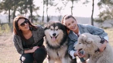 Genç güzel kadınlar gülümsüyor ve sevimli köpekleriyle sarılıyorlar.