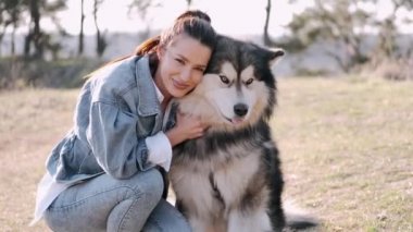 Güzel kız tarlada sevimli tüylü bir köpekle yürüyor.