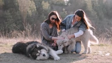 Genç güzel kadınlar gülümsüyor ve sevimli köpekleriyle sarılıyorlar.