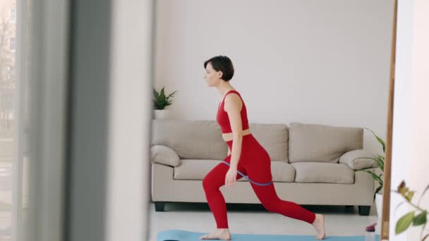 Женщина делает упражнения на попку с фитнес-группой — стоковое видео