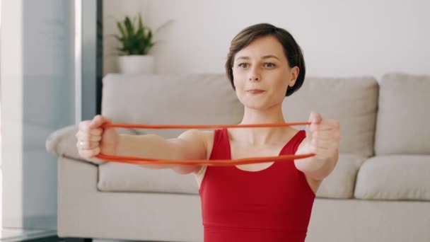 Спортивная женщина в красном костюме делает упражнения с фитнес-группой — стоковое видео