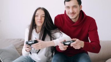 Güzel bir kız ve bir oğlan oturma odasında video oyunu oynuyorlar.
