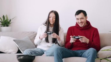 Güzel bir kız ve bir oğlan oturma odasında video oyunu oynuyorlar.