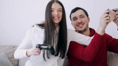 Güzel bir kız ve bir oğlan oturma odasında video oyunu oynuyorlar.