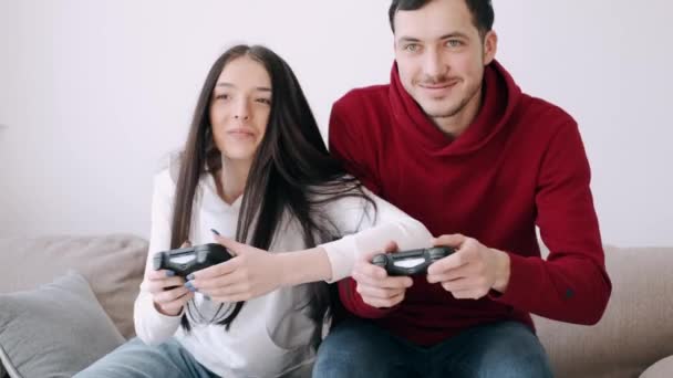 Egy csinos lány és egy fiú videojátékoznak a nappaliban. — Stock videók