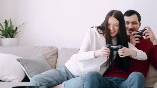 Uma menina bonita e um menino estão jogando videogames na sala de estar — Vídeo de Stock