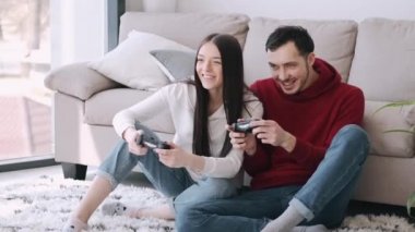 Güzel bir kız ve bir oğlan oturma odasında video oyunu oynuyorlar.