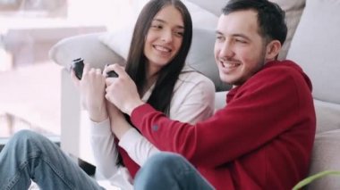 Güzel bir kız ve bir oğlan oturma odasında video oyunu oynuyorlar.