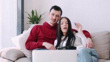 Güzel genç çift dizüstü bilgisayarda film izliyor ve patlamış mısır yiyor.