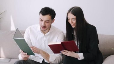 Yakışıklı bir adam ve güzel bir kız defterlerinde bir şeyler okuyorlar.