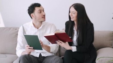 Yakışıklı bir adam ve güzel bir kız defterlerinde bir şeyler okuyorlar.