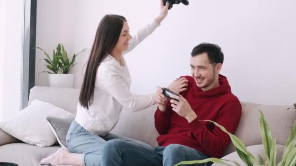 Uma menina bonita e um menino estão jogando videogames na sala de estar — Vídeo de Stock