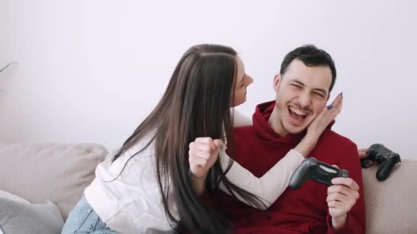 Una bella ragazza e un ragazzo stanno giocando ai videogiochi in salotto — Video Stock