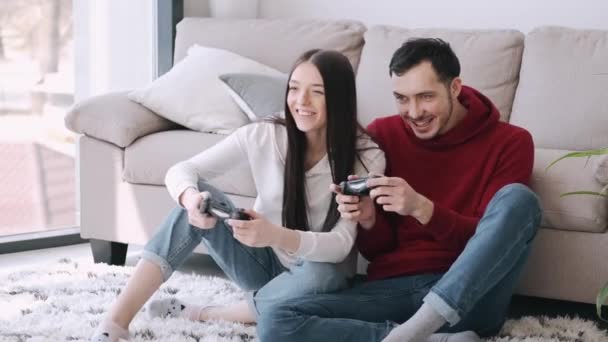 Een mooi meisje en een jongen spelen videospelletjes in de woonkamer. — Stockvideo