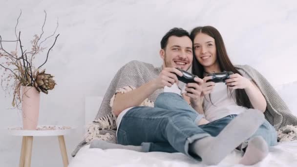 Mooi meisje en vriend zijn spelen station in bed — Stockvideo