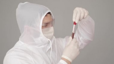 Tam donanımlı erkek bilim adamı bir laboratuvarda kan testini inceliyor.
