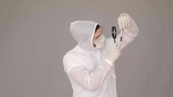 Homme scientifique examine un test sanguin avec une loupe — Video