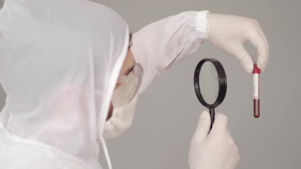 Científico masculino está examinando un análisis de sangre con una lupa — Vídeos de Stock