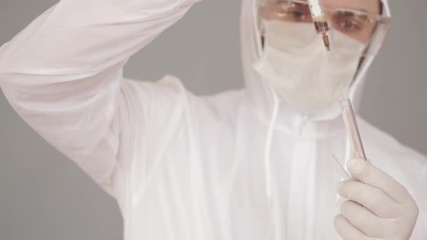 Le scientifique dans l'équipement de couverture complète collocage blodd d'un essai avec une seringue — Video