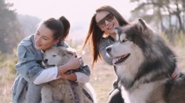 Genç güzel kadınlar gülümsüyor ve sevimli köpekleriyle sarılıyorlar.