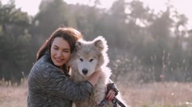 Güzel kız tarlada sevimli tüylü bir köpekle yürüyor.