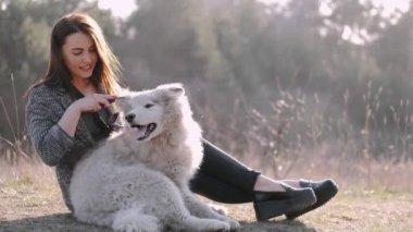 Güzel kız tarlada sevimli tüylü bir köpekle yürüyor.