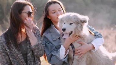 Genç güzel kadınlar gülümsüyor ve sevimli köpekleriyle sarılıyorlar.