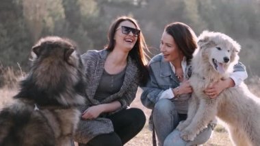 Genç güzel kadınlar gülümsüyor ve sevimli köpekleriyle sarılıyorlar.