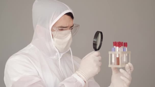 Férfi tudós vizsgálja a vérvizsgálat egy nagyító — Stock videók