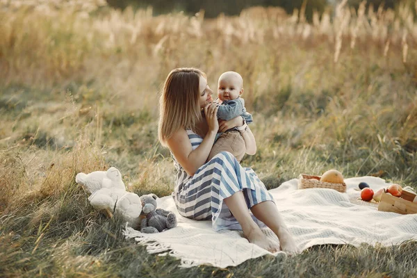Madre con piccolo figlio seduto in un campo autunnale — Foto Stock