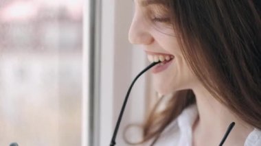 Gözlüklü güzel kadın pencerenin yanında gülümsüyor.